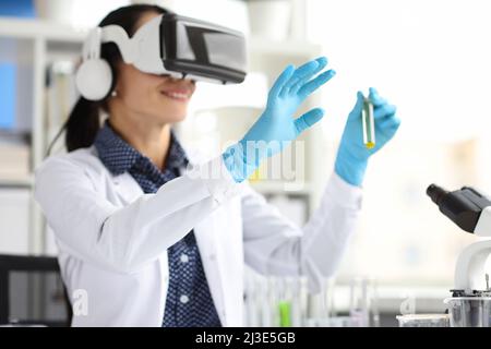 Médecin en lunettes virtuelles tient les tubes à essai en clinique Banque D'Images