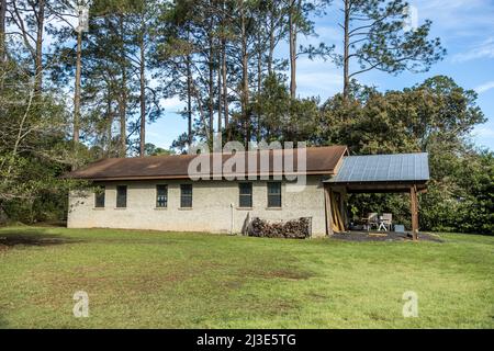 Bâtiment de stockage extérieur en stuc au-dessus des murs de blocs de cinder avec une toiture régulière et en métal avec une pile de bois pour l'hiver Banque D'Images