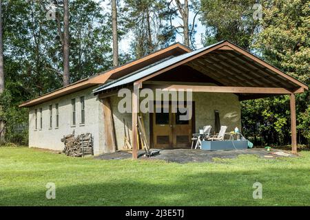 Bâtiment de stockage extérieur en stuc au-dessus des murs de blocs de cinder avec une toiture régulière et en métal avec une pile de bois pour l'hiver Banque D'Images