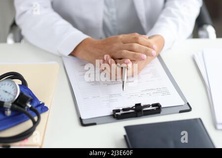 Le médecin tient le stylo et le dossier médical à la clôture du lieu de travail Banque D'Images