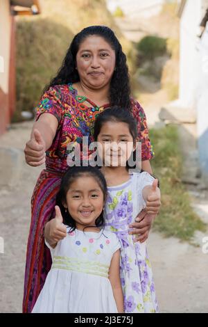 Latina mère avec ses deux filles heureuses à l'extérieur de sa maison dans la zone rurale - les femmes hispaniques avec le pouce vers le haut Banque D'Images