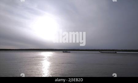 Paysage naturel avec une rivière au début de l'hiver et la lumière froide du soleil reflétée dans la surface de l'eau clip. Forêt en pleine distance et calme Banque D'Images