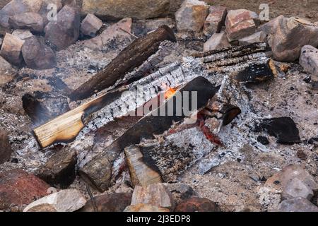 Feu de camp entouré de rochers sur une plage de sable. Banque D'Images