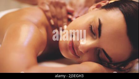 C'est toujours le bon moment pour se faire dorloter. Gros plan d'une belle jeune femme bénéficiant d'un massage du dos dans un spa de beauté. Banque D'Images