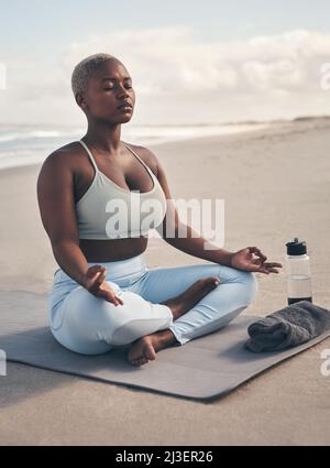 Le yoga m'a aidé à trouver une maison en moi-même. Photo d'une femme méditant pendant sa routine de yoga sur la plage. Banque D'Images