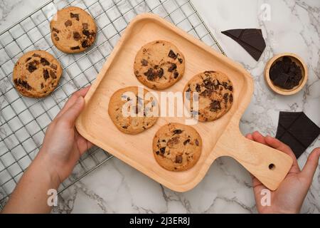 Vue de dessus, femelle tenant un plateau en bois avec des biscuits doux fraîchement cuits au-dessus de l'espace de cuisson. Banque D'Images