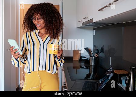 jeune femme afro-américaine moderne prenant le petit déjeuner et travaillant à la maison Banque D'Images