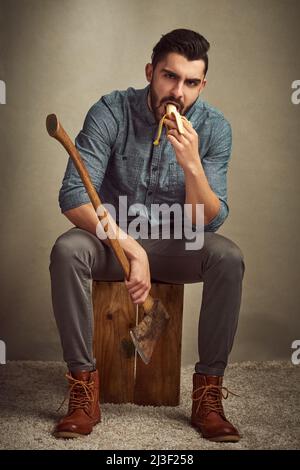 Il le maintient en bonne santé et fort. Studio photo d'un jeune homme posant avec une hache sur fond vert. Banque D'Images