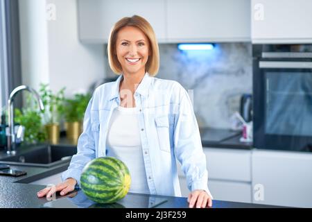 Une jeune femme adulte s'occupe de la cuisine avec de la pastèque Banque D'Images