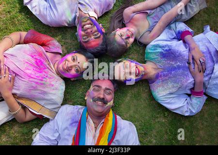Portrait d'une famille indienne heureuse couché sur l'herbe avec des visages colorés sur Holi Banque D'Images
