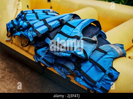 Ces gars peuvent sauver votre vie. Photo d'une pile de gilets de sauvetage de rafting en rivière qui se trouvent au-dessus d'un bateau de rafting en rivière en caoutchouc à l'extérieur pendant la journée. Banque D'Images