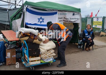 Medyka, Pologne. 6th avril 2022. Un volontaire israélien avec Erenezer, l'Agence juive pour Israël, emboîte des couvertures pour les réfugiés à la frontière entre l'Ukraine et la Pologne, sous un drapeau avec une étoile juive de David. Des milliers de réfugiés ukrainiens qui passent avec succès en Pologne à pied après avoir échappé à la terreur de Poutine dans leur pays entrent dans le camp frontalier de Medyka, où une masse de bénévoles internationaux compatissants sont prêts aux aider à chaque étape de la mise en sécurité et de leur nouveau foyer. (Image de crédit : © Amy Katz/ZUMA Press Wire) Banque D'Images