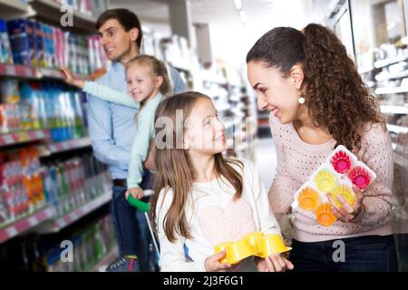 Parents avec deux enfants achetant du yogourt aux fruits Banque D'Images