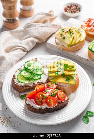 Sandwiches sur du pain de seigle et de blé avec feta, légumes, fruits et herbes fraîches. Vue latérale, verticale. Des collations saines. Banque D'Images