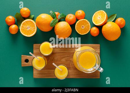 Jus d'orange fraîchement pressé dans un pichet en verre et fruits frais avec feuilles, boisson saine, concept de vitamine C, vue sur le dessus Banque D'Images