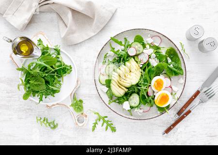 Salade de légumes frais à l'avocat et aux œufs durs avec radis, concombre, épinards, arugula et fromage cottage. Vue de dessus Banque D'Images