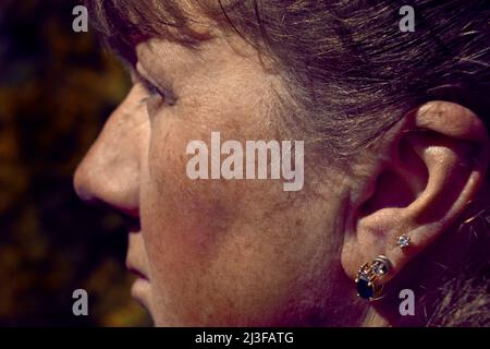 Portrait d'une femme adulte pensive avec boucles d'oreilles dans son oreille Banque D'Images
