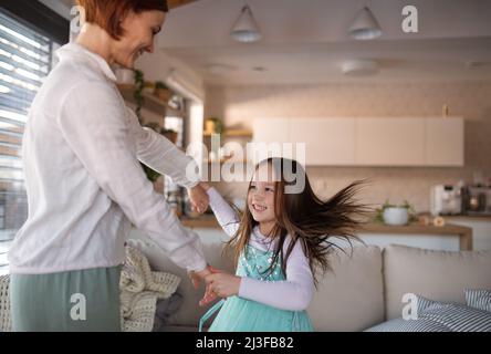 Bonne mère s'amuser avec sa petite fille en costume de princesse à la maison. Banque D'Images