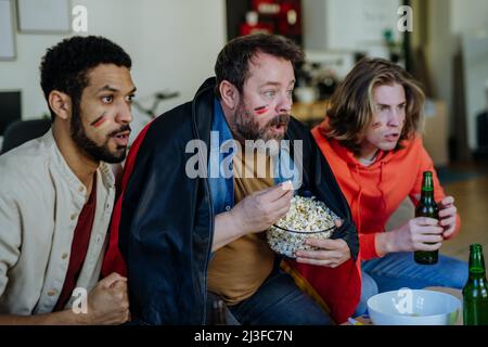 Des fans de football nerveux regardent des amis de l'équipe nationale allemande lors d'un match de football en direct à la télévision à la maison Banque D'Images