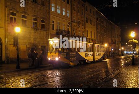 Service de tramway la nuit sous la pluie, place Rynok, centre-ville, Lviv, Ukraine Banque D'Images