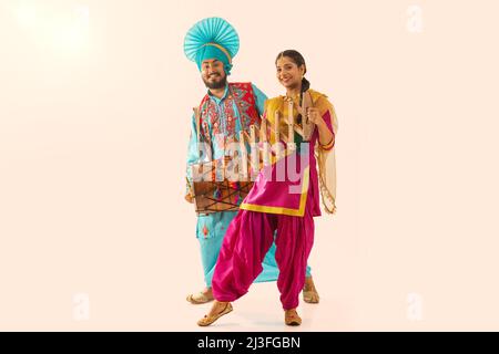 Couple Sikh exécutant bhangra avec tambour et sapp pendant la célébration Baisakhi Banque D'Images