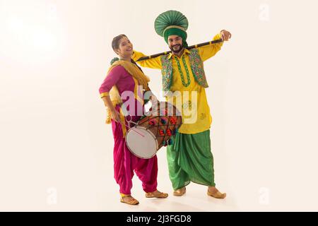 Le couple sikh exécutant le bhangra avec le tambour et le khunda pendant la célébration de Baisakhi Banque D'Images