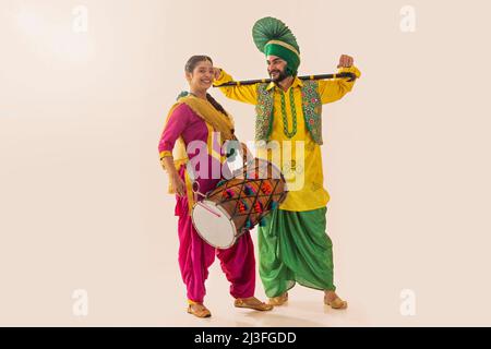 Le couple sikh exécutant le bhangra avec le tambour et le khunda pendant la célébration de Baisakhi Banque D'Images