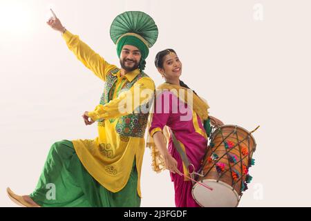 Le couple Sikh exécutant bhangra et jouant au tambour pendant la fête de Baisakhi Banque D'Images