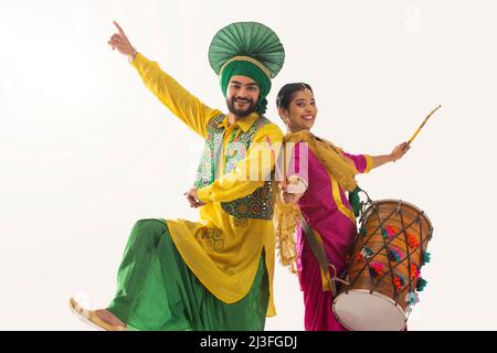 Le couple Sikh exécutant bhangra et jouant au tambour pendant la fête de Baisakhi Banque D'Images