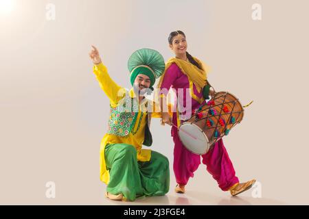 Le couple Sikh exécutant bhangra et jouant au tambour pendant la fête de Baisakhi Banque D'Images