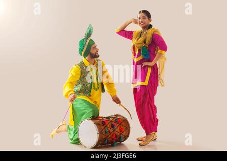 Le couple Sikh exécutant bhangra et jouant au tambour pendant la fête de Baisakhi Banque D'Images