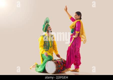 Le couple Sikh exécutant bhangra et jouant au tambour pendant la fête de Baisakhi Banque D'Images