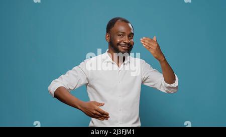 Homme afro-américain montrant des mouvements de danse robot en studio, faisant la danse de fête unique et le mouvement sur la musique urbaine contemporaine. Un homme qui se déplace sur un son disco avec une action robotique. Banque D'Images