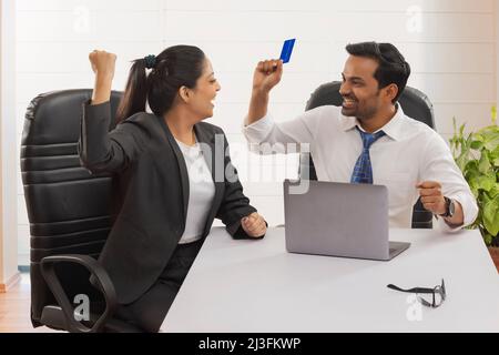 Heureux couple d'affaires applaudissent avec les Fists de levage après la transaction réussie en utilisant la carte de crédit Banque D'Images