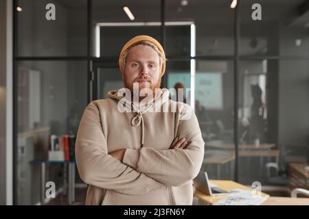 Portrait d'un jeune développeur d'applications caucasiennes avec une barbe debout avec une tasse thermos et une tablette au bureau Banque D'Images