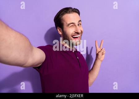 Photo du brunet millénaire impressionné Guy do selfie Blink porter un t-shirt violet isolé sur fond violet Banque D'Images