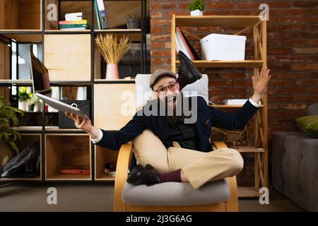 Portrait d'un jeune barbu, Happy yogi faisant de l'exercice de yoga sur un fauteuil à la maison au travail. Concept d'affaires, mode de vie sain, sport Banque D'Images