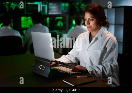 Scientifique de recherche médicale féminine utilisant un ordinateur portable. Neurologue résolvant les puzzles de l'esprit et du cerveau. Dans le laboratoire avec plusieurs écrans Banque D'Images