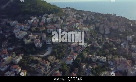 Le quadcopter survole la ville. ATTACHE. Une vue panoramique de la ville située dans une zone montagneuse sur le bord de mer Banque D'Images