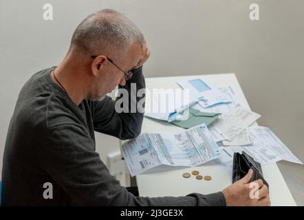 Homme mature assis à la maison, stressé et confus par calculer les dépenses de la facture ou de la facture, n'ont pas d'argent à payer, hypothèque ou prêt. Dette, faillite Banque D'Images