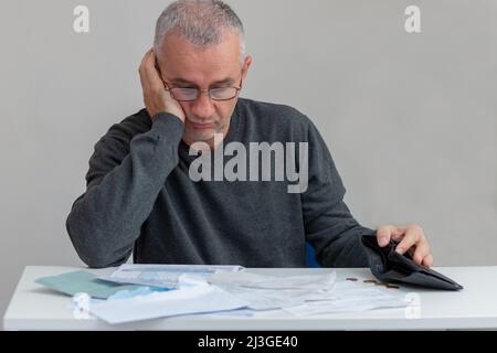 Homme mature assis à la maison, stressé et confus par calculer les dépenses de la facture ou de la facture, n'ont pas d'argent à payer, hypothèque ou prêt. Dette, faillite Banque D'Images