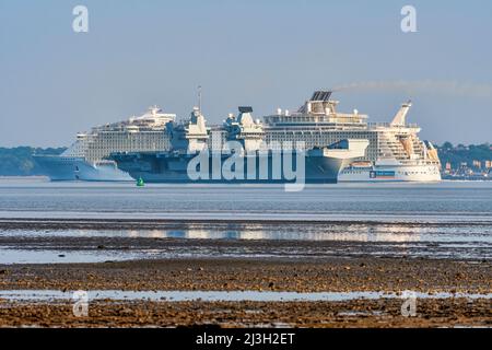 Le porte-avions de la Marine royale HMS Queen Elizabeth (R08), à l'ancre dans le Solent, est passé par le navire de croisière encore plus grand allure of the Seas. Banque D'Images