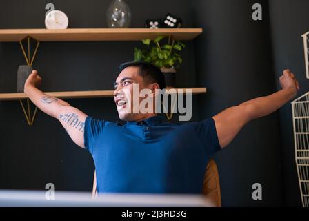 Un jeune homme asiatique avec des tatouages s'étire à son bureau et nageait au bureau Banque D'Images