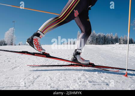 Ski de fond, gros plan de l'athlète avec skis, bottes et bâtons, colline enneigée en arrière-plan Banque D'Images