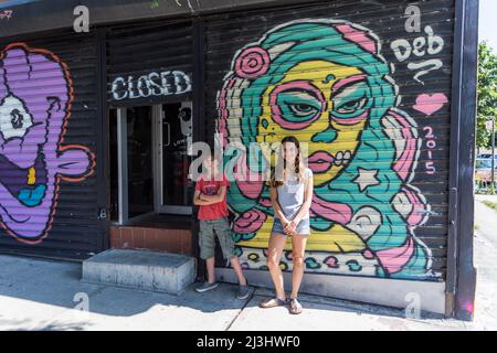 Bushwick, New York City, NY, États-Unis, jeune fille de 14 ans de race blanche et adolescent de 12 ans de race blanche - tous deux avec des cheveux bruns et un style d'été devant un Graffiti Banque D'Images