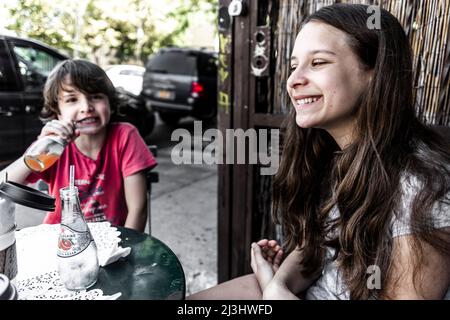 Bushwick, New York City, NY, États-Unis, jeune fille de 14 ans de race blanche et adolescent de race blanche de 12 ans, tous deux avec des cheveux bruns et un style d'été dans un café Banque D'Images