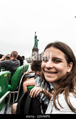 Hudson River, New York City, NY, États-Unis, jeune fille de 14 ans de race blanche et adolescent de 12 ans de race blanche - tous deux avec des cheveux bruns et un style d'été sur le monstre à côté de la statue de la liberté Banque D'Images