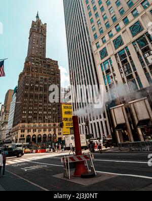 5 AV/W 58 ST, New York City, NY, USA, vue sur la rue typique de New York City. Vie active, gens, magasins, drapeaux américains, voitures et un bain de vapeur au milieu de la rue. Banque D'Images