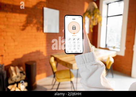 Femme tenant son téléphone avec l'application de sécurité intelligente pour la maison Banque D'Images