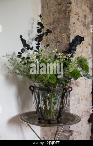 Bouquet moderne de fleurs dans un vase en verre décoratif sur une table de commande Banque D'Images